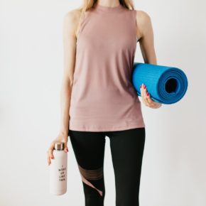 crop sportswoman carrying sport mat and bottle of water before exercising